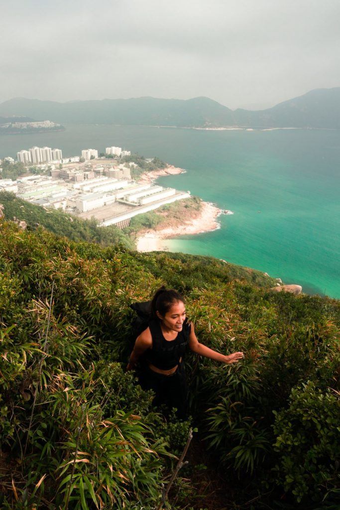 海の近くの急な丘をハイキングする女性。