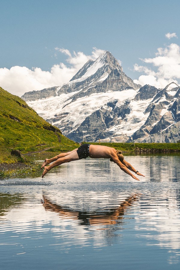 山を背景に湖に飛び込む男性。