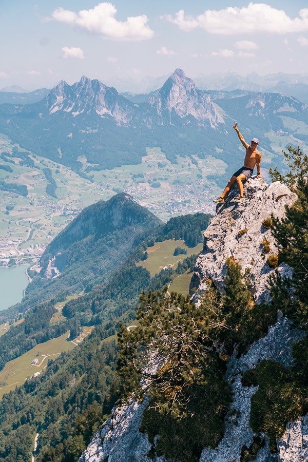 山の頂上に腕を上げて座っている男性。