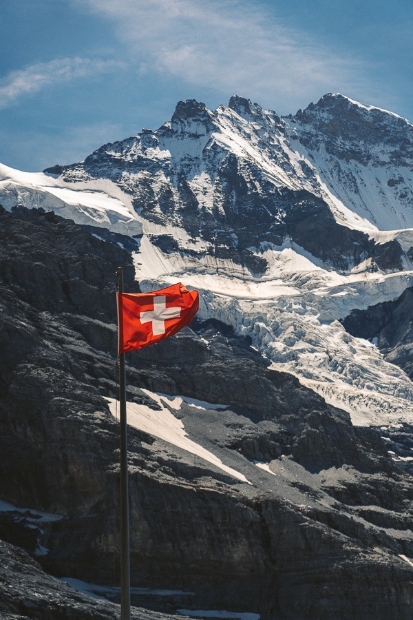山の前にはためくスイスの国旗。